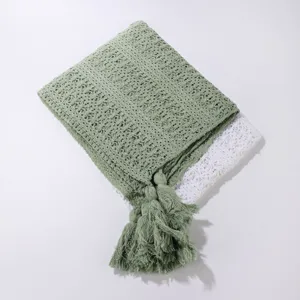 Detailed view of women knitted hollow shawl cape with elegant tassels in soft green color.