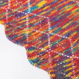Nahaufnahme bunter Strickstoff, lebendige Häkeltextur mit geschwungener Saumkante.
