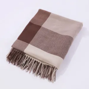 Close-up detail of a brown and beige plaid winter shawl scarf with decorative fringe.