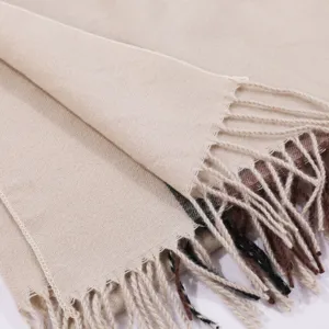 Close-up of beige winter shawl fringe fabric detail texture and soft warm scarf edge trim.