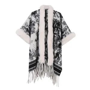 Detailaufnahme des schwarz-weißen Strick-Capes mit flauschigem Kunstfellkragen und Fransen.