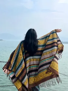 Detailansicht eines ethnischen Fransenumhangs mit Muster, gemütliche Reisekleidung draußen.
