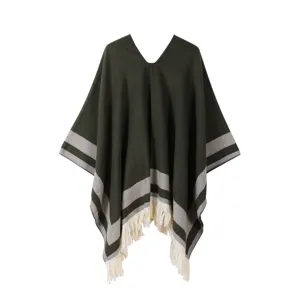 Close-up of the cozy dark green knit poncho featuring elegant grey stripes and soft fringe.