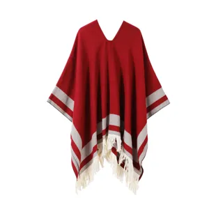 Red grey striped poncho detail, white fringe tassel edge, soft knit fabric texture closeup.