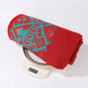 Coperta in tessuto rosso con motivo geometrico, dettaglio che mostra il peso esatto del prodotto.
