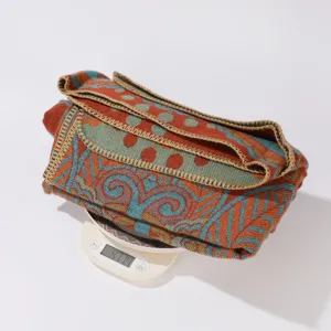 Detalle de manta tejida jacquard mostrando peso en báscula, diseño retro boho.