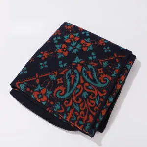 Detailed view of women's knitted shawl, stylish paisley pattern, cozy winter accessory.