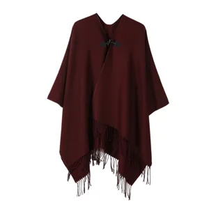 Gros plan détaillé de la cape poncho en tricot à franges avec bouton et ourlet.