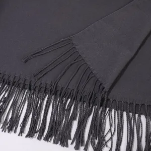 Détail de frange d'écharpe châle tricoté gris foncé, texture douce d'hiver gros plan.