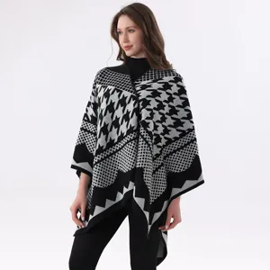 Detailaufnahme des schwarz-weißen Hahnentritt-Strickponchos mit stilvollem Schlitz.