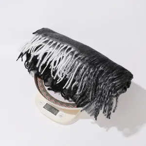 Detailed view of black and white gradient fringe scarf showing product weight on scale.