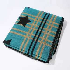 Nahaufnahme Detail des teal- und goldfarbenen karierten Winterschals mit Sternenmuster.