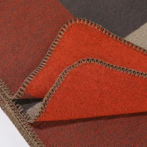 Detail des Strickschals mit weicher strukturierter orange-grauer Farbblock-Webmuster.