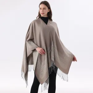 Detailansicht eines eleganten khakifarbenen Ponchos mit geometrischem Muster und Fransen.