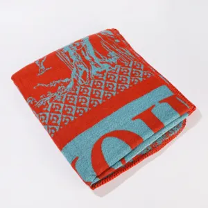 Coperta scialle in maglia rossa e blu con motivi geometrici e dettagli di testo.