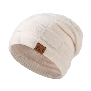 Nahaufnahme der gefütterten Strickmütze mit stilvollem Karomuster und vorderem Lederaufnäher.
