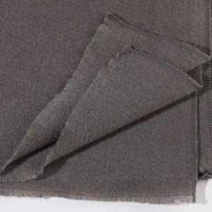 Close-up detail shot of the soft dark grey knitted scarf showing its fine texture and fringe edges.