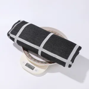 Detail view of black and white plaid shawl, rolled up on digital scale showing weight.