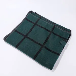 Detailed view of dark green plaid shawl folded neatly, showing black grid and side strap.