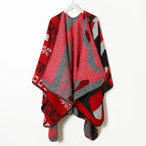 Detailed view of the red and grey knitted poncho with geometric patterns and soft woolen fabric.