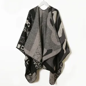 Detailed view of knitted black grey patterned cape shawl, soft texture geometric winter wear.