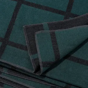 Close-up detail shot of the dark green and black plaid cape fabric texture and edge stitching.