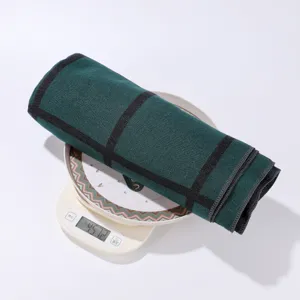 Detailed view of the dark green plaid shawl rolled up on a scale, showing fabric texture and weight.