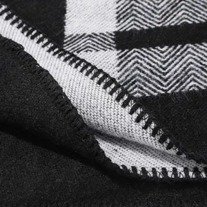 Detailed view of the thick knitted plaid shawl showing fine overlock stitching and texture.