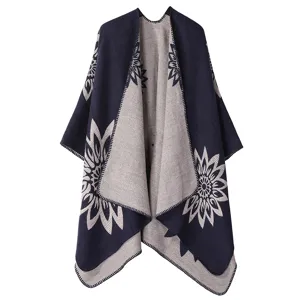Nahaufnahme des stilvollen Strickponchos mit auffälligem Sonnenblumenmuster und Kontrastfarbdesign.