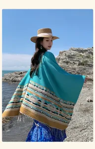 Vista dettagliata della mantella scialle etnica color-block indossata da una modella sulla spiaggia.