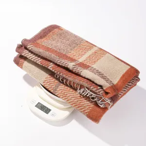 Detail view of a cozy autumn and winter plaid knitted scarf and tassel shawl in brown tones.