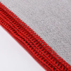 Detailed view of cashmere-like shawl knit fabric edge with red overlock and gray texture.