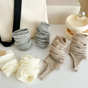 Detail view of knitted ballet stirrup leg warmers, showing fine ribbed texture and stylish stacked calf design.
