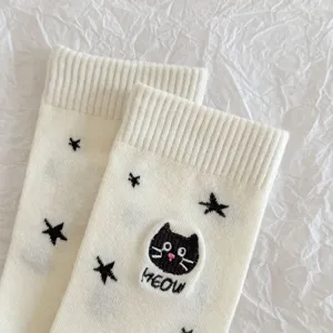 Close up of cute cat embroidered mid-calf socks with black star pattern on white cotton.