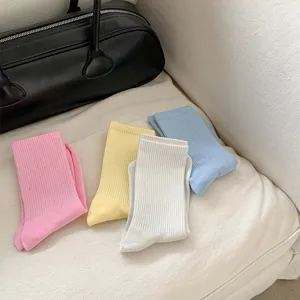 Close-up detail shot of colorful ribbed mid-tube socks in pastel pink, yellow, white, and blue.