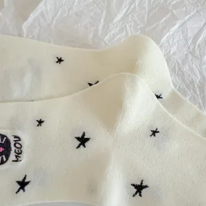 Detailed view of white cotton mid-tube socks featuring cute black star patterns and cat embroidery.