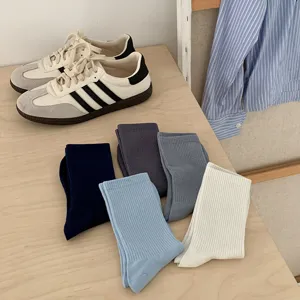 Detail view of colorful ribbed cotton mid tube socks displayed neatly on wooden table surface.