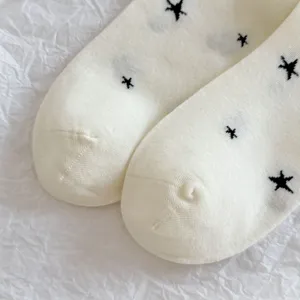 Close-up of women's white socks featuring cute black star embroidery and soft breathable fabric.