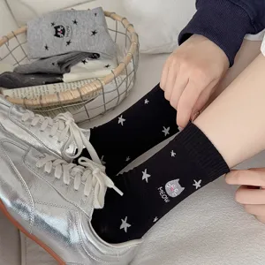 Detailed shot of cute cat and star embroidered black mid-calf socks worn with silver sneakers.