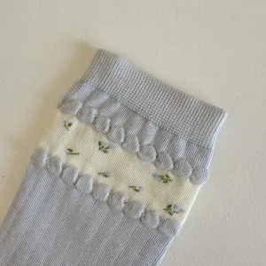 Women slouch socks detail close up, cute floral embroidery and bubble cuff knit design.
