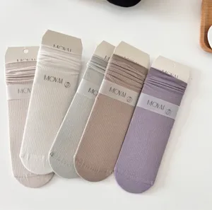 Close-up detail of solid color breathable mesh crew socks with rolled cuff and paper card.