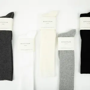 Detailed view of solid color long knee socks with packaging bands, soft knit texture.