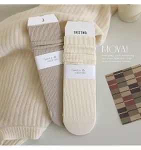 Detail shot of cozy ribbed slouch socks in beige and off-white, soft cotton knit texture.