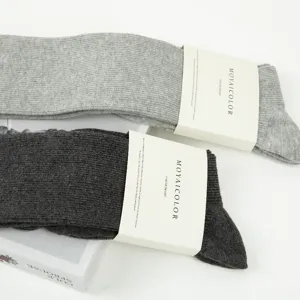 Detailed view of long ribbed cotton socks in light and dark grey with brand paper bands.
