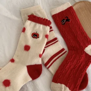 Primer plano de calcetines de invierno rojos y blancos acogedores con bordado de gato y suave tejido.