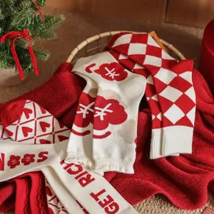 Détail de chaussettes d'hiver en tricot rouge et blanc avec motifs de cœur et carreaux festifs.