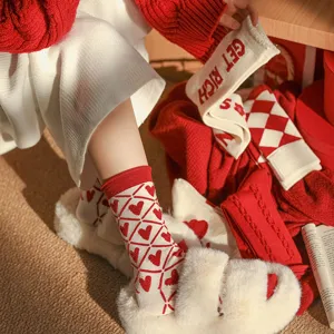 Gros plan de chaussettes en laine rouges et blanches douillettes avec motif cœur pour femmes.
