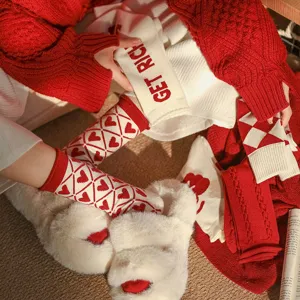 Vue detail de chaussettes laine carreaux rouges hiver douillet, texture douce et chaleureuse.