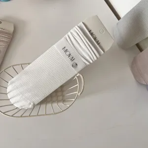 Detail view of white ribbed crew socks for women, breathable knit pattern with nice tag.