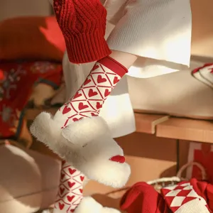 Gros plan de chaussettes en laine chaudes d'hiver avec motif de cœur rouge et blanc festif.